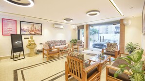 A hotel lobby with a reception desk, seating area, and large windows offering a view of the street. - Fabhotel Prime Atithyam (Gurugram)
