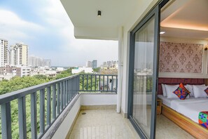 Ein Balkon mit Blick auf die Stadt, ein Bett mit bunten Kissen und eine Wand mit Muster.