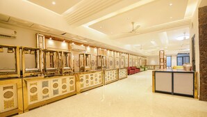A spacious lobby with a long reception desk, multiple seating areas, and a modern ceiling design. - Fabhotel Prime Atithyam (Gurugram)