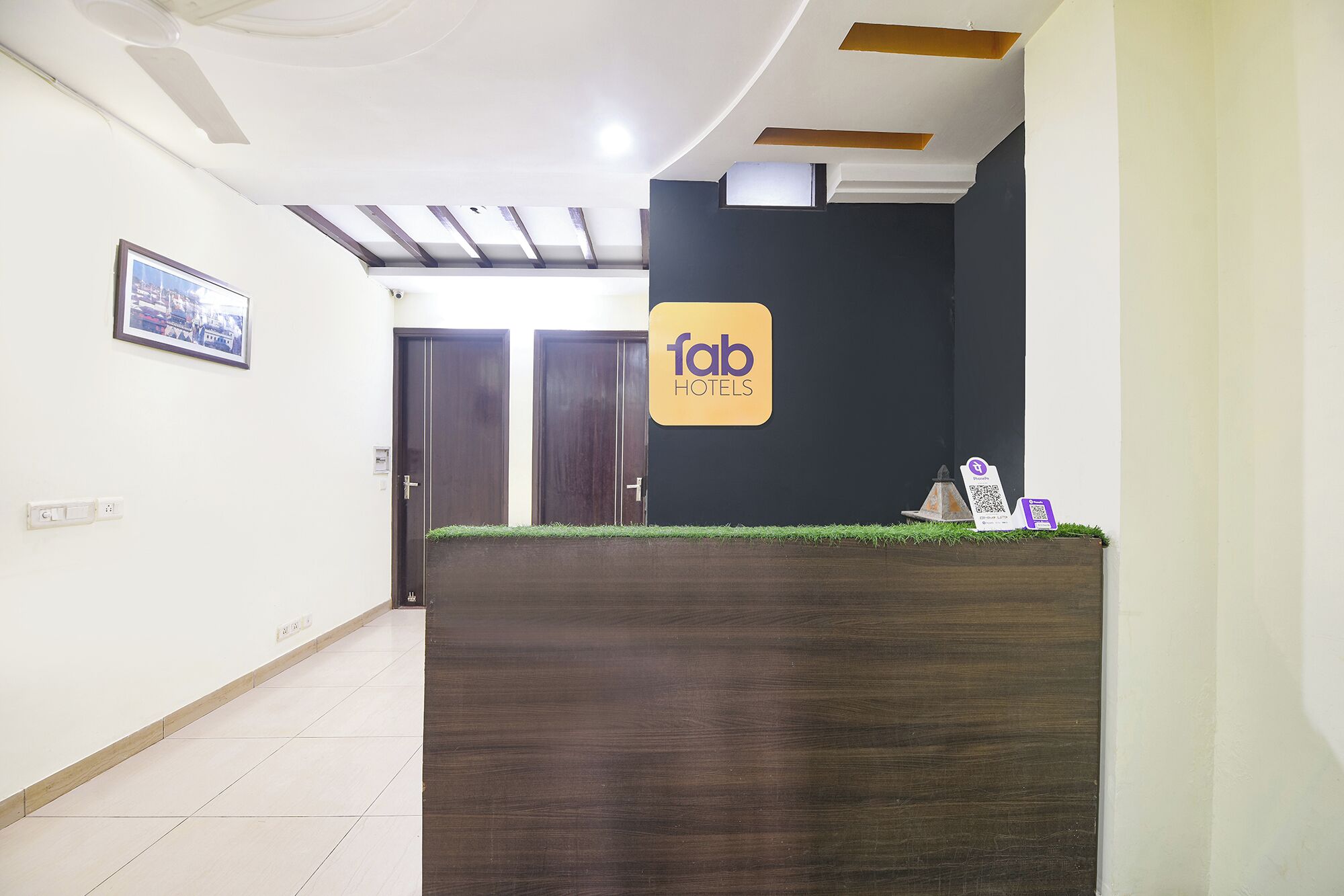 A reception desk with a logo, a framed picture on the wall, and a door in the background.