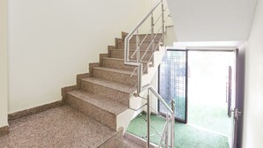 Un escalier avec une rampe métallique menant à une porte surmontée d’un portail en métal.