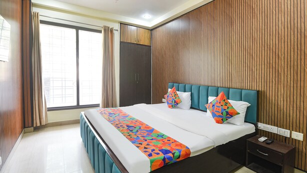 Une chambre d’hôtel avec un grand lit, une table de chevet, un ventilateur de plafond et une fenêtre avec des rideaux.