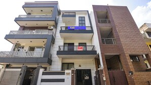 Un immeuble à plusieurs étages, doté d’une architecture moderne, avec des balcons et une entrée sécurisée par un portail.