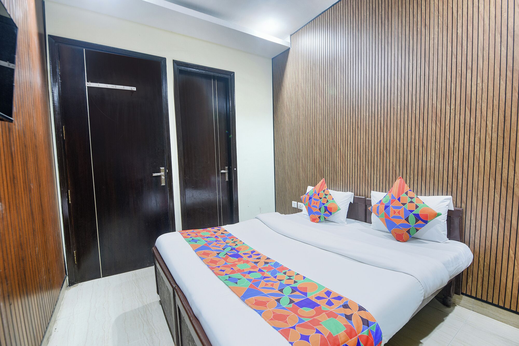 A bedroom with a bed, two pillows, a wooden wall, and a door.