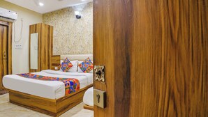 A bedroom with a wooden bed frame, a patterned headboard, and a large mirror. - Fabhotel Shri Vilas (Bhopal)