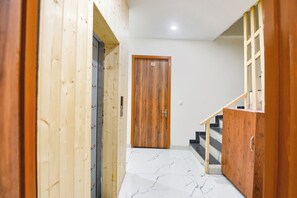 A hallway with a wooden door, a staircase, and a tiled floor. - Fabhotel Royal Metro (Amritsar)
