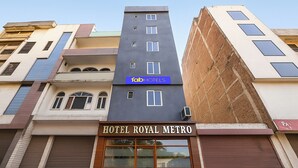 Ett hotell som heter ”HOTEL ROYAL METRO” med en modern fasad, en blå skylt med texten ”abHOTELS” och en stängd persienn på höger sida.