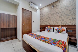 A bedroom with a bed, a wardrobe, and a wall-mounted air conditioner. - Fabhotel Nrm Residency (Mysore)