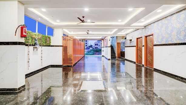 A hotel corridor with marble flooring, wooden doors, and a ceiling fan. - Fabhotel Leon Square (Bengaluru)