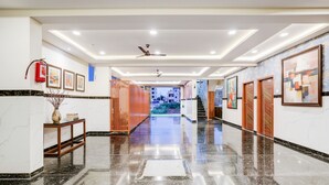 A polished hallway with a marble floor, framed artwork on the walls, and a fire extinguisher on the left. - Fabhotel Leon Square (Bengaluru)