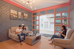 A modern living room with a sofa, coffee table, and large windows. - Fabhotel East Land (Bangalore)