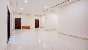 A spacious hallway with marble flooring, two doors, and a sofa. - Fabhotel Palm Bliss (Unnao)