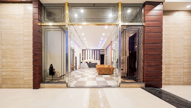 A hotel lobby with a checkered floor, a reception desk, and a seating area. - Fabhotel Palm Bliss (Unnao)