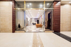 A hotel lobby with a checkered floor, a reception desk, and a seating area. - Fabhotel Palm Bliss (Unnao)