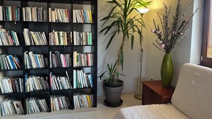 Un salon avec une bibliothèque, une plante en pot, une lampe et un canapé.
