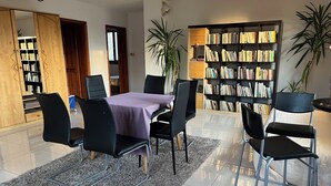 Un coin repas comprenant une table, des chaises, une bibliothèque et une plante.