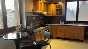 Une cuisine moderne avec des meubles en bois, un plan de travail noir et un coin repas équipé de deux chaises.