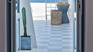An open doorway leading to a balcony with a view of the sea and distant mountains. - Namaste Suites by Oias Local Cavehouses (Oia)