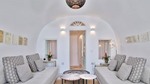 A modern living room with two sofas, a coffee table, and a decorative lamp. - Namaste Suites by Oias Local Cavehouses (Oia)