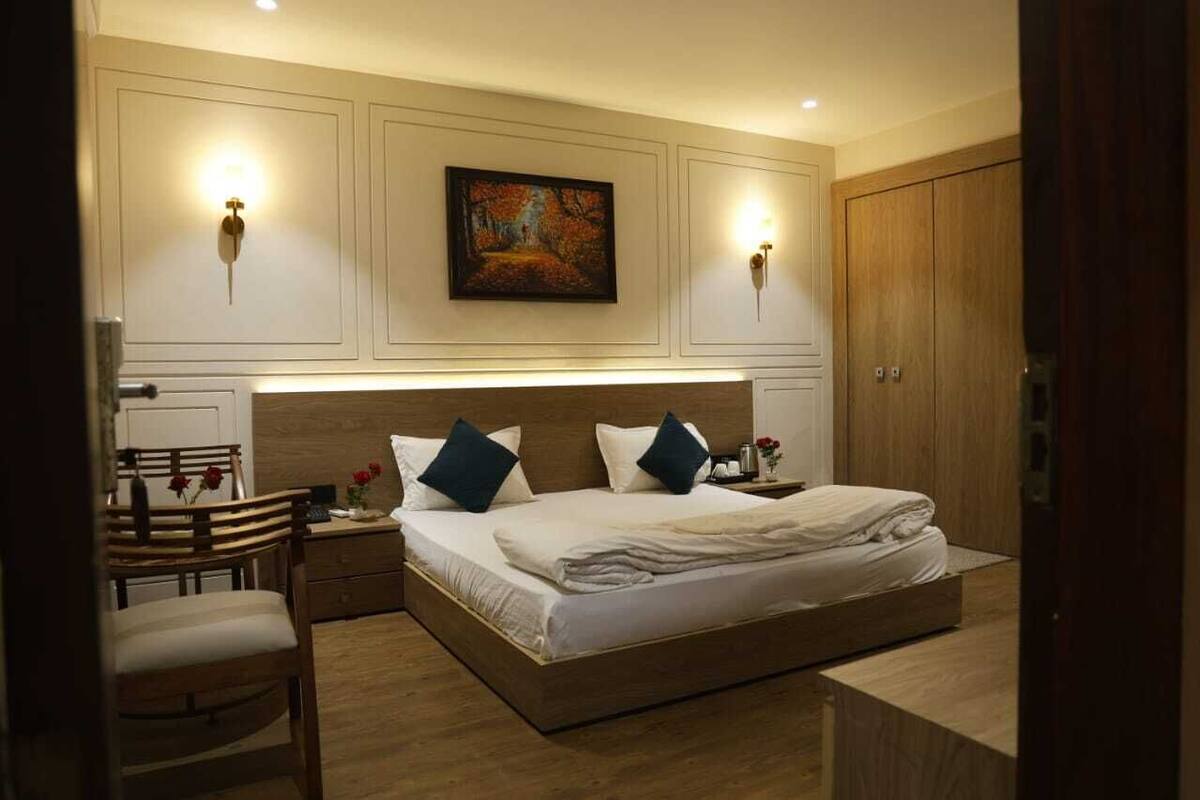 Ein Schlafzimmer mit einem großen Bett, zwei Wandleuchten, einem Gemälde über dem Bett und einem Holzschrank.