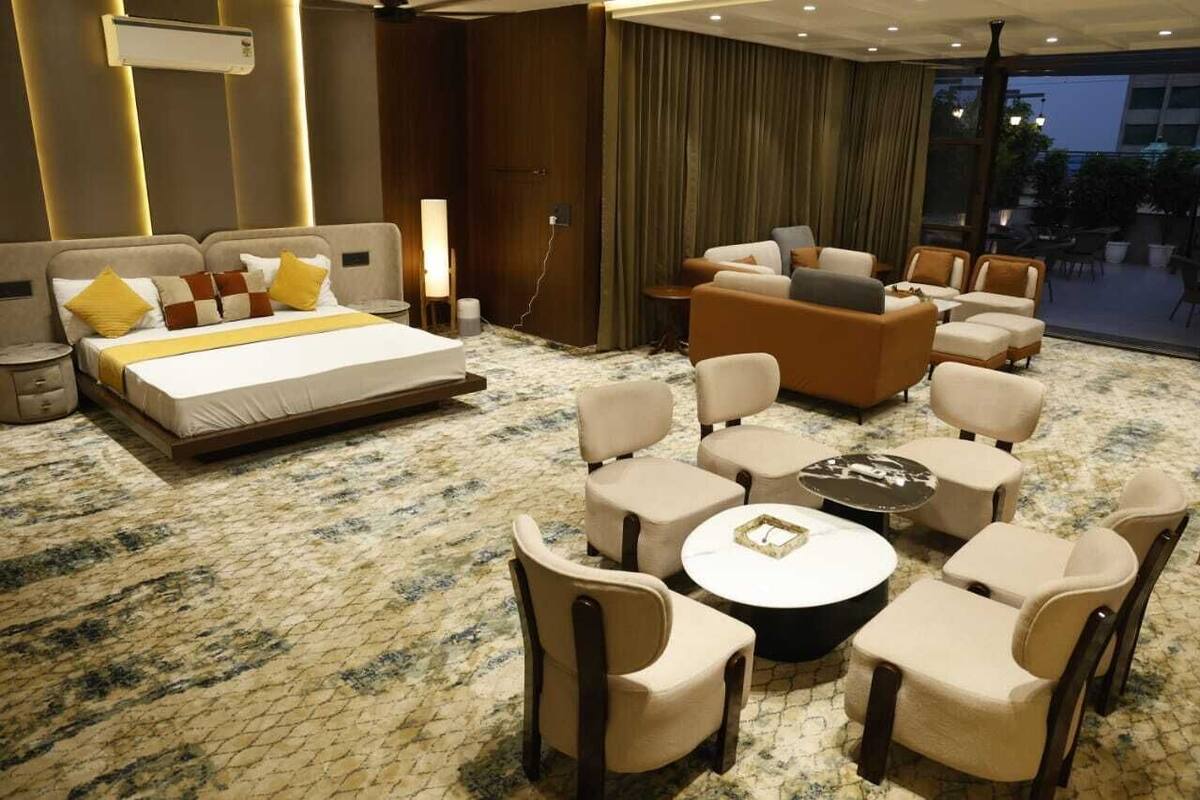 Ein Hotelzimmer mit einem großen Bett, einer Couch und mehreren Sesseln, die um einen Couchtisch angeordnet sind.
