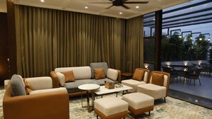 A modern living room with a sofa set, ottomans, and a coffee table. - Siya Residency (New Delhi)