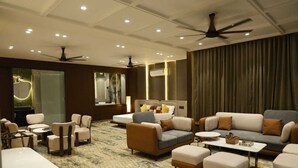 A hotel lobby with a seating area, a large sofa, a coffee table, and a ceiling fan. - Siya Residency (New Delhi)