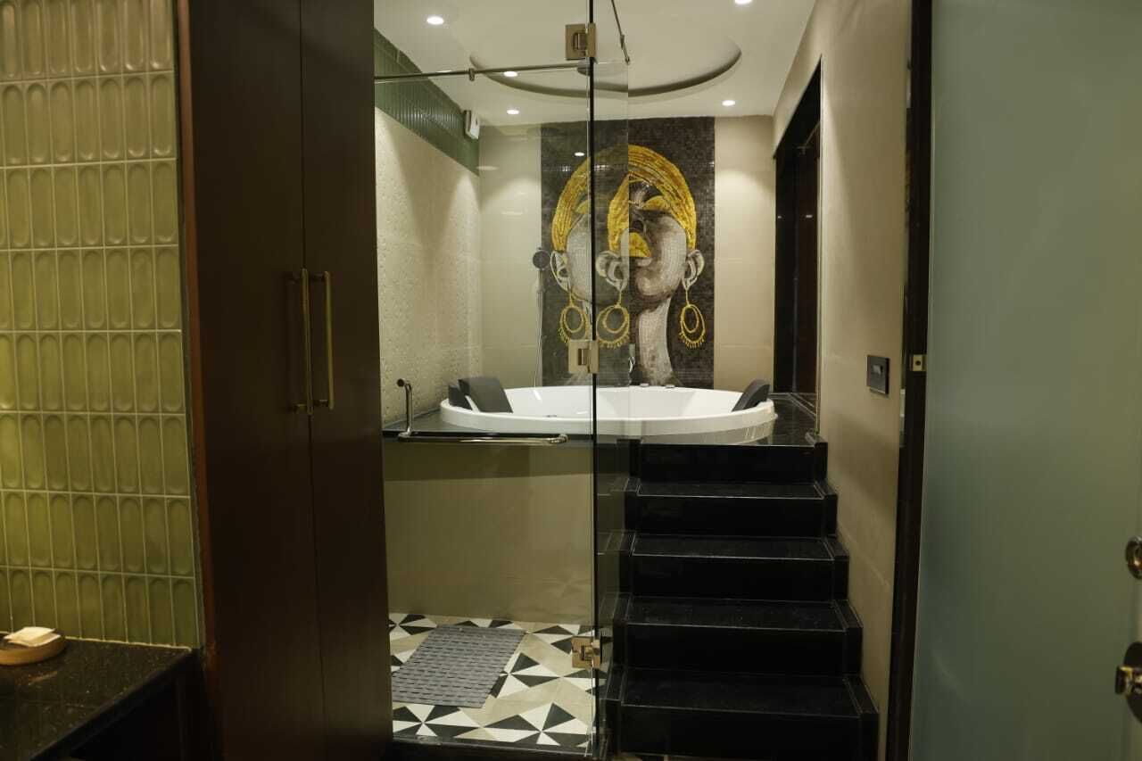 Ein modernes Badezimmer mit einer gläsernen Duschkabine, einer schwarzen Badewanne und einem geometrischen Fliesenboden.