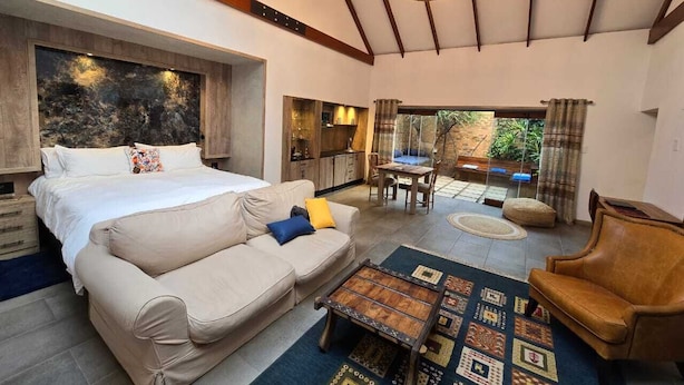 Una habitación amplia con una cama, un sofá, una mesa de centro y una zona de comedor.