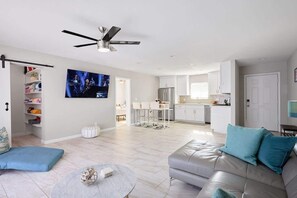 Un salon moderne avec un canapé, une table basse, un téléviseur et un ventilateur de plafond.
