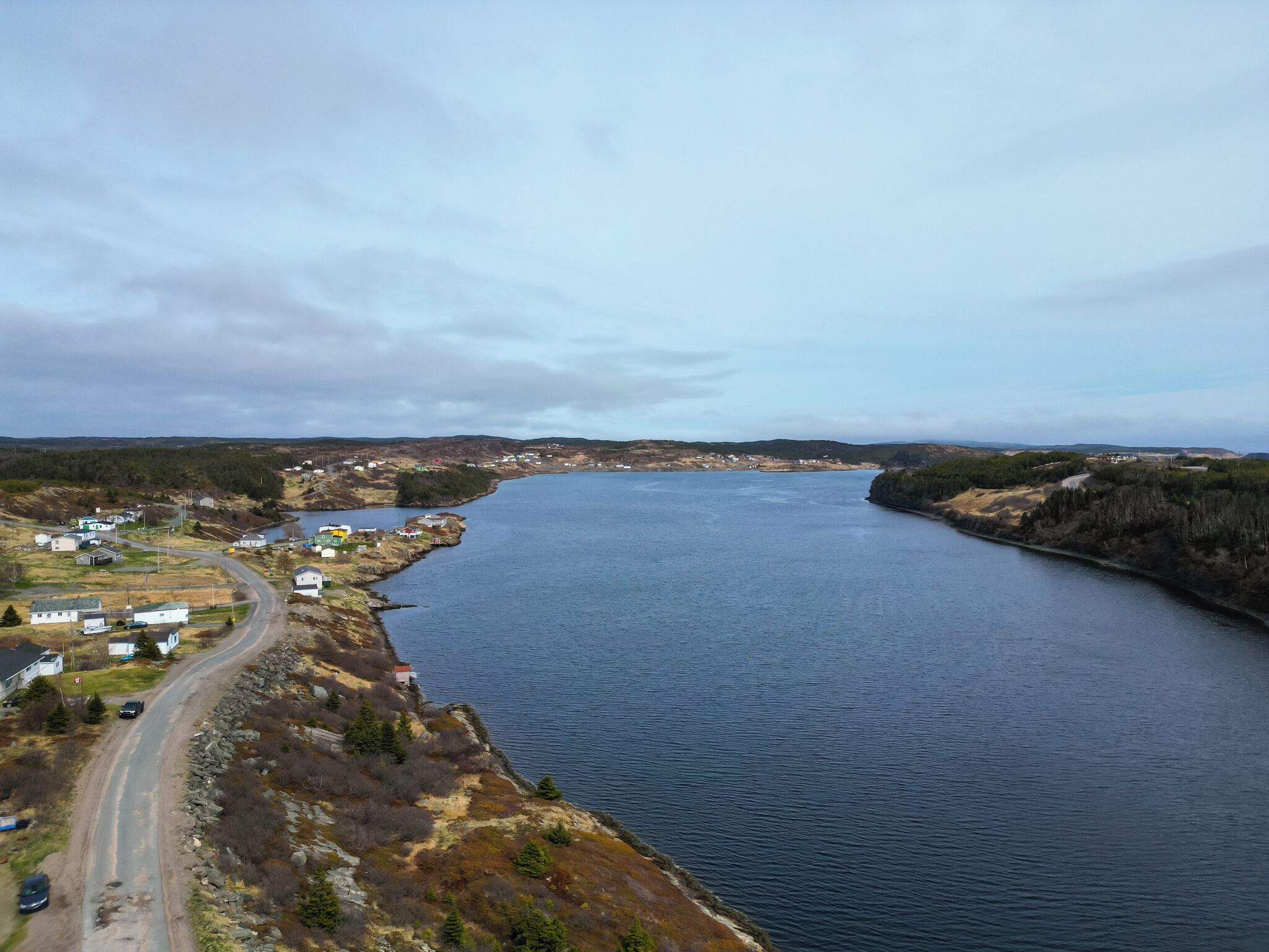 A coastal town with a river, houses, and a road curving along the water.