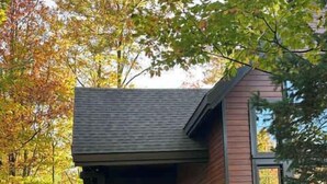 A modern house with a covered porch and a small patio area. - Nature & confort | Refuge L'Equilibre (Scott)