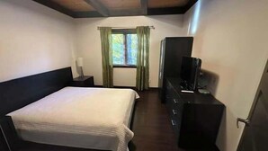 A bedroom with a bed, a dresser, a television, and a window with curtains. - Nature & confort | Refuge L'Equilibre (Scott)
