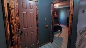A hallway with wooden doors and a bunk bed in the background.