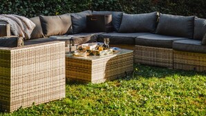 A cozy outdoor seating area with wicker furniture and cushions, surrounded by lush greenery. - Deauville Lovely Flat With Private Garden (Tourgeville)