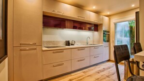 A modern kitchen with wooden cabinets, a sink, and a dining area with chairs. - Deauville Lovely Flat With Private Garden (Tourgeville)