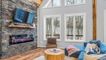 Relax by the warmth of this cozy living room while taking in the snow covered trees outside.