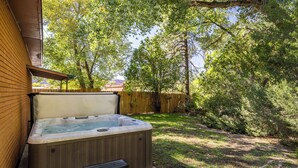 Un jacuzzi con revestimiento de madera, un taburete y una valla de madera al fondo.