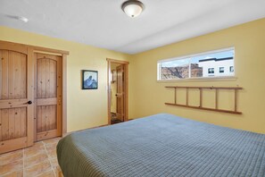 A bedroom with a bed, wooden wardrobe, a window with a view, and a door leading to another room.