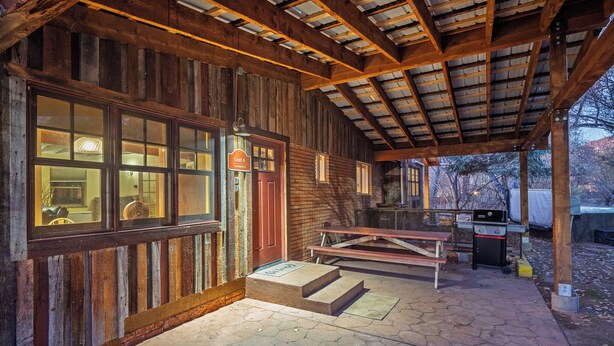 A rustic wooden building with a covered patio, a barbecue grill, and a bench. - New Listing! Charming Moab Hideaway | Steps from Main Street (Moab)