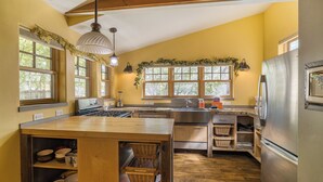A kitchen with a wooden island, stainless steel appliances, and large windows with greenery. - New Listing! Charming Moab Hideaway | Steps from Main Street (Moab)