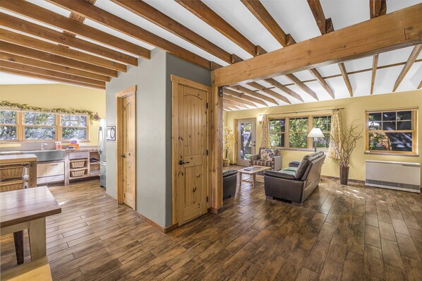 A spacious room with wooden beams on the ceiling, a kitchen area with a sink and cabinets, and a seating area with a sofa and chairs. - New Listing! Charming Moab Hideaway | Steps from Main Street (Moab)