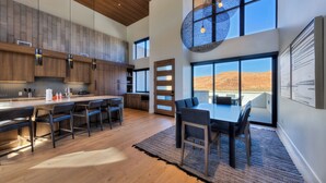 Una cocina moderna con una isla grande, taburetes de bar y un comedor con vistas al desierto.