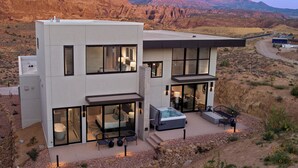 Una casa moderna de dos plantas con ventanas amplias, un jacuzzi y un patio con mobiliario.