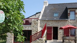 A stone building with a red staircase, a bench, and a red umbrella. - Charming stone cottage near Guérande (Guérande)