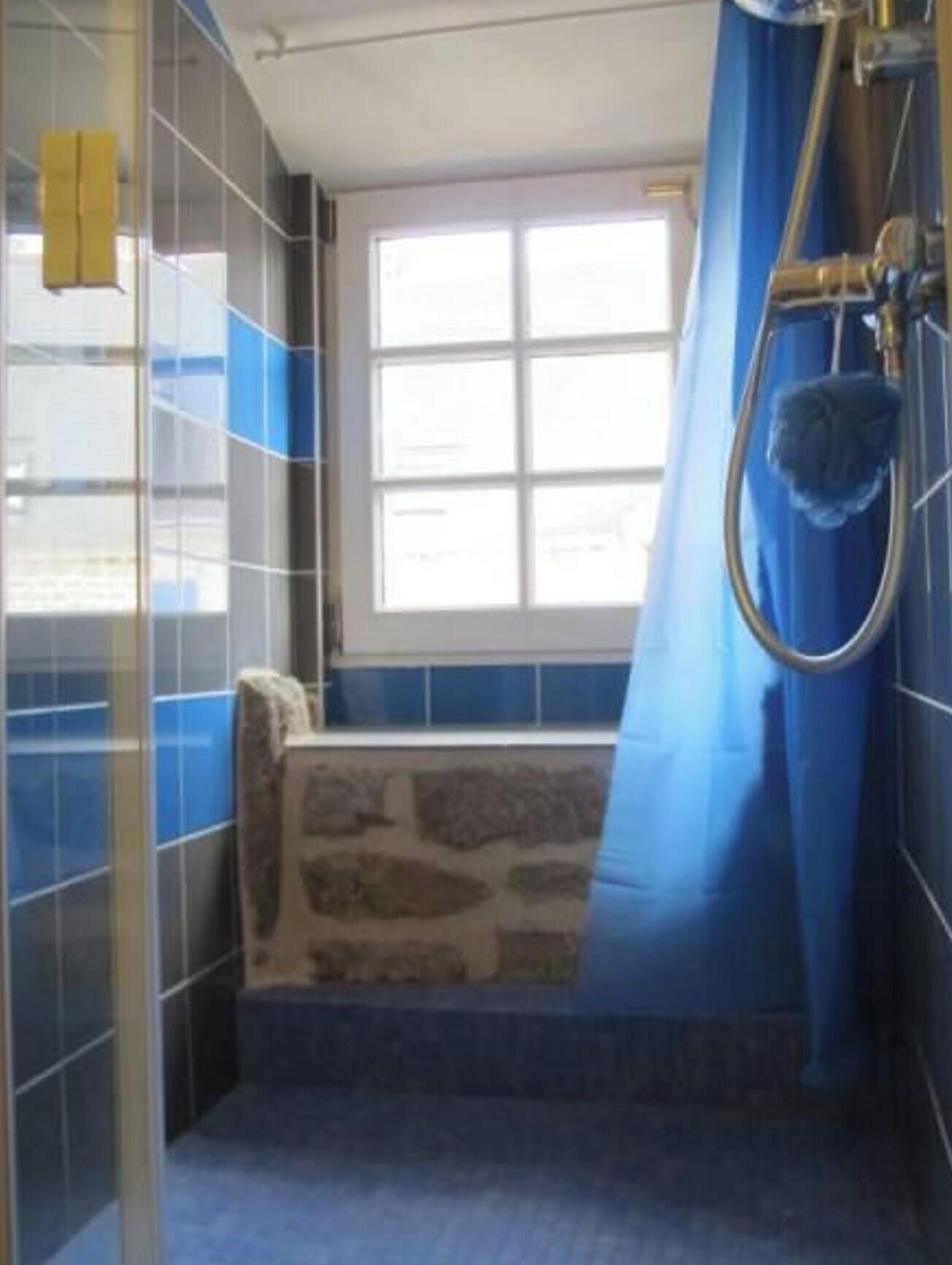 A bathroom with a stone wall, a window, and a shower area.