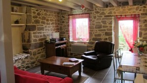 A stone-walled room with a fireplace, a sofa, a chair, and a table.