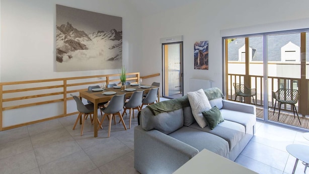 A modern living room with a dining area, a sofa, and a balcony with a view.