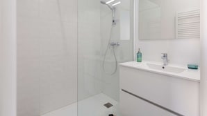 A modern bathroom with a glass-enclosed shower, a white sink, and a mirror above the sink.