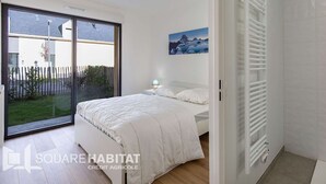 A bedroom with a bed, a window, a painting, and a radiator.